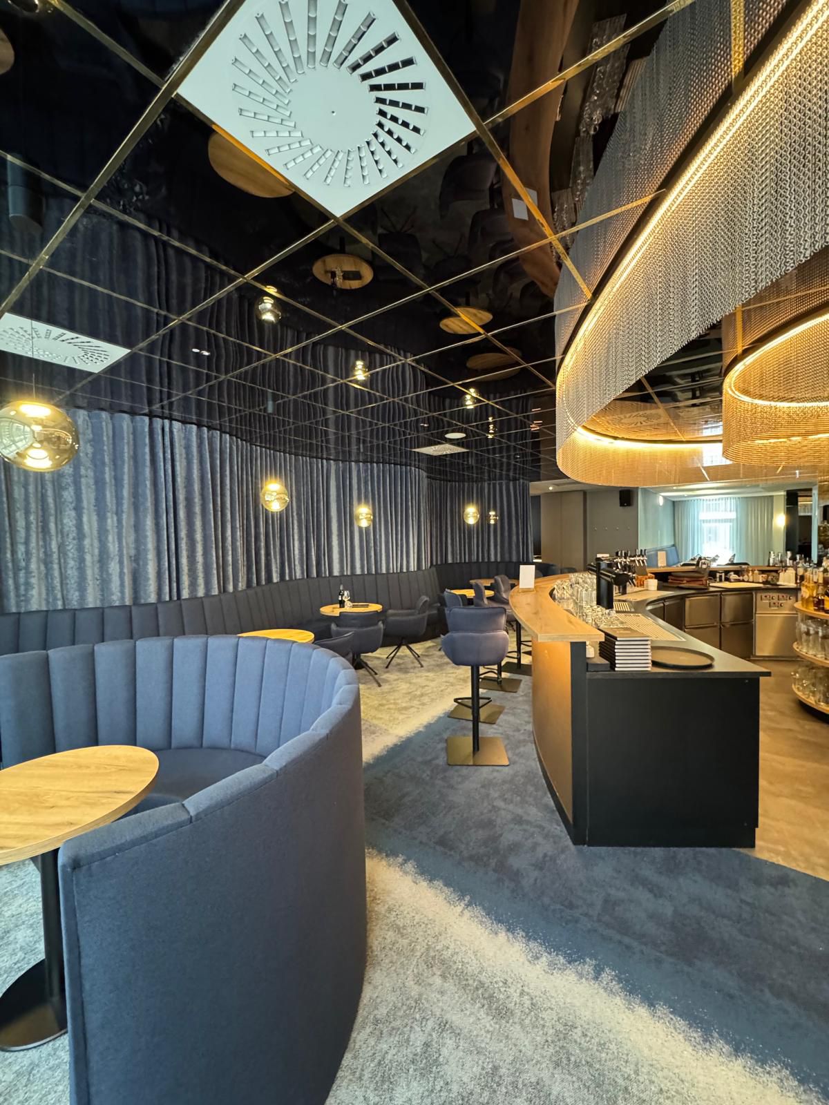 Modern elegante Bar mit blauen Sitznischen goldenen Lampen und geschwungenem Tresen